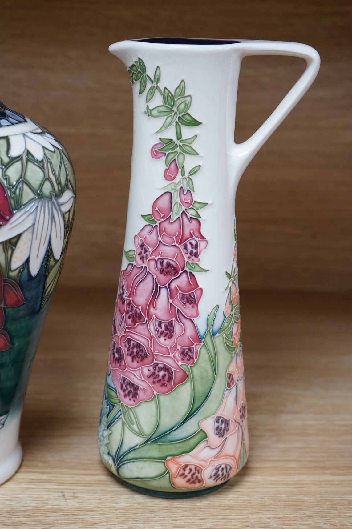 A Moorcroft ‘Nostalgia’ pattern vase together with a similar ‘Foxglove’ pattern ewer, 24.5cm. Condition - good, some crazing